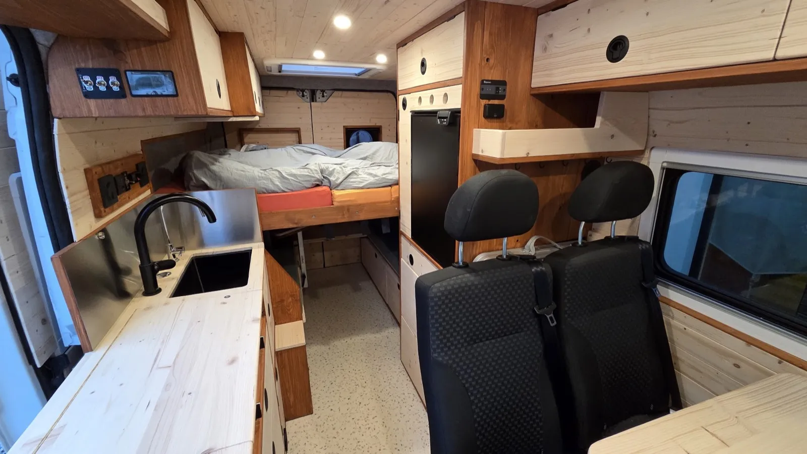Intérieur fini du van — cuisine, lit, rangements, sièges
